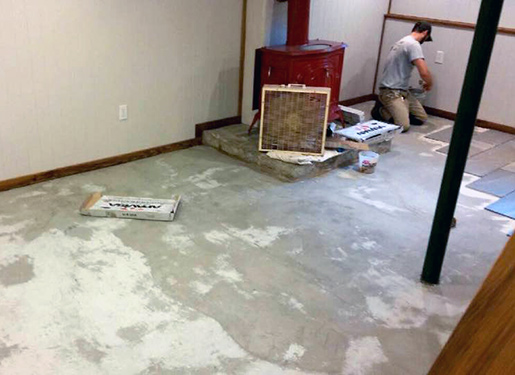 Kyle Swanson tiling a basement floor